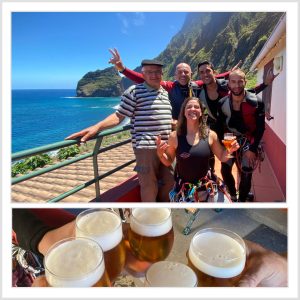 a group of people posing for a photo drinking beers by the beach