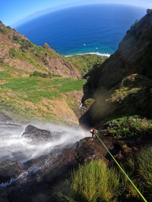 a body of water with a mountain in the background and someone doing canyoning